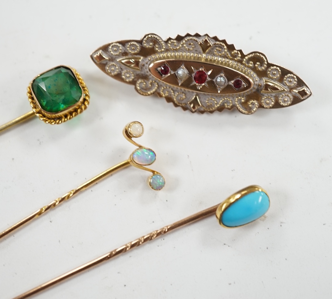 An Edwardian 9ct, ruby and seed pearl set cannetille work brooch, 46mm, together with three assorted gem set stick pins. Condition - fair